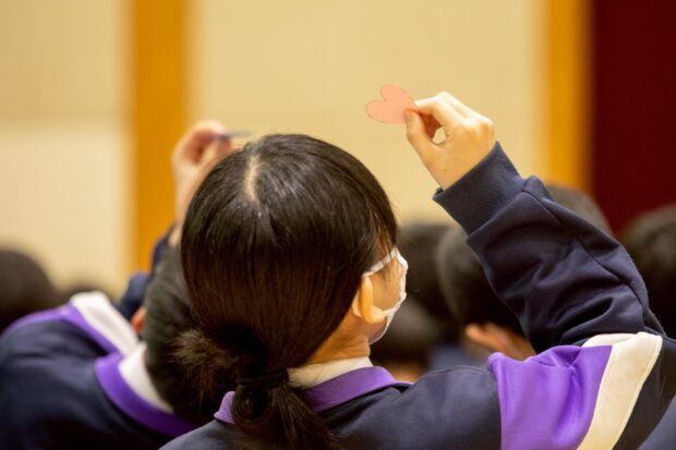 中学生がハートの紙をみている写真